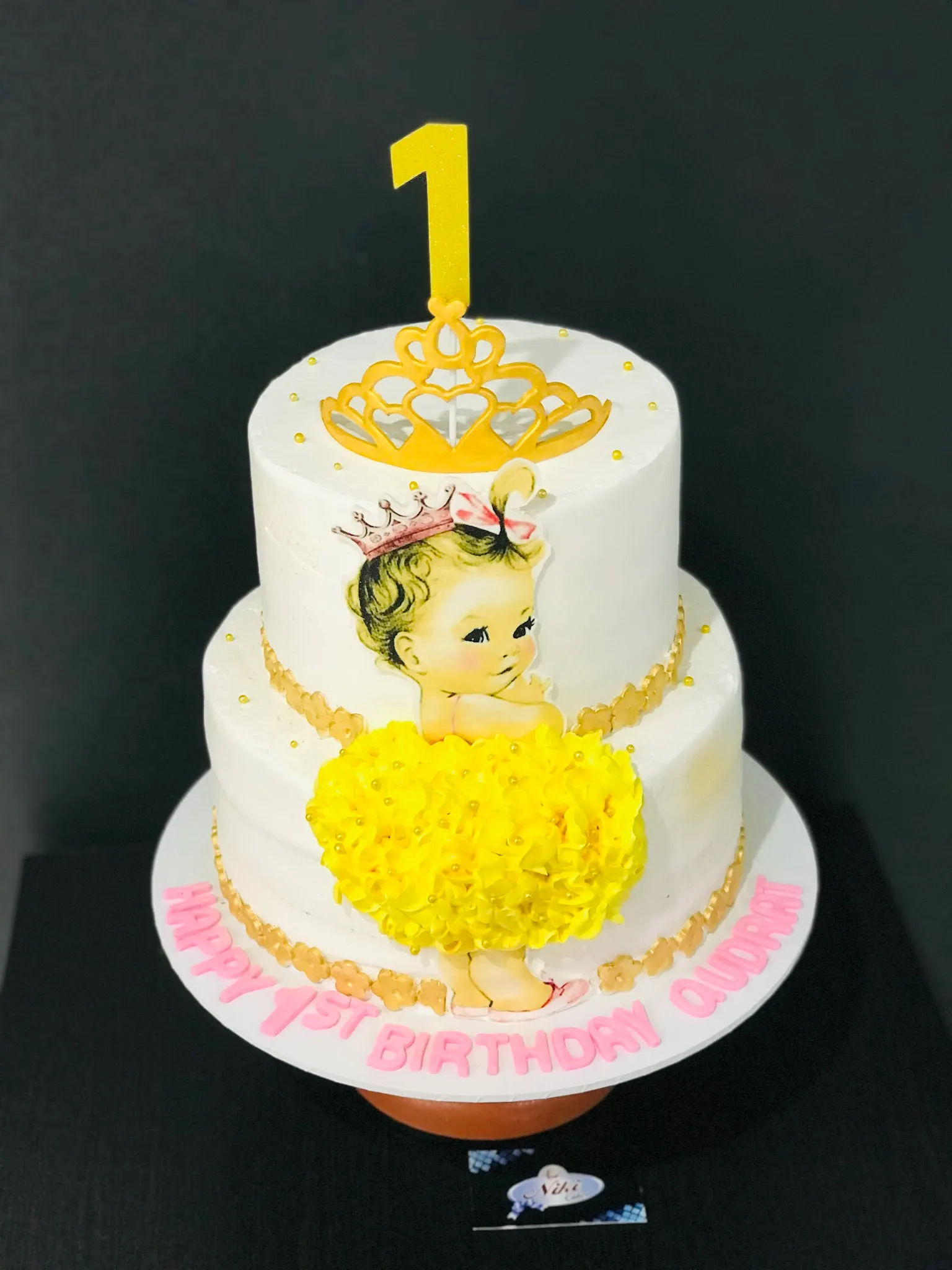 Two-tier white princess birthday cake with gold tiara, vintage baby illustration and yellow ruffle skirt